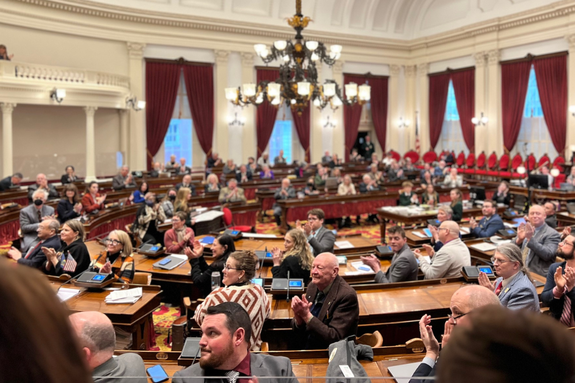 The House chamber at the Vermont State House showing representatives clapping