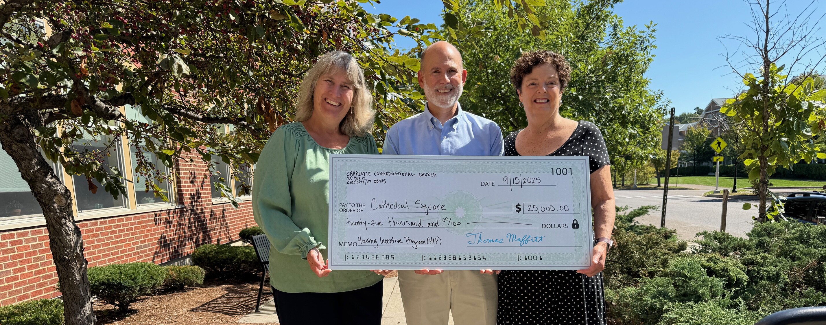 Photo of three people holding a big check