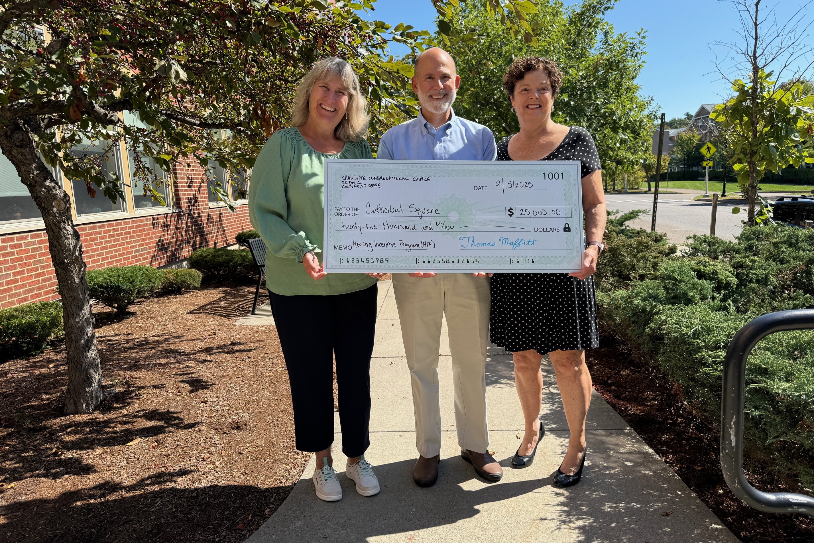 Photo of three people holding a big check