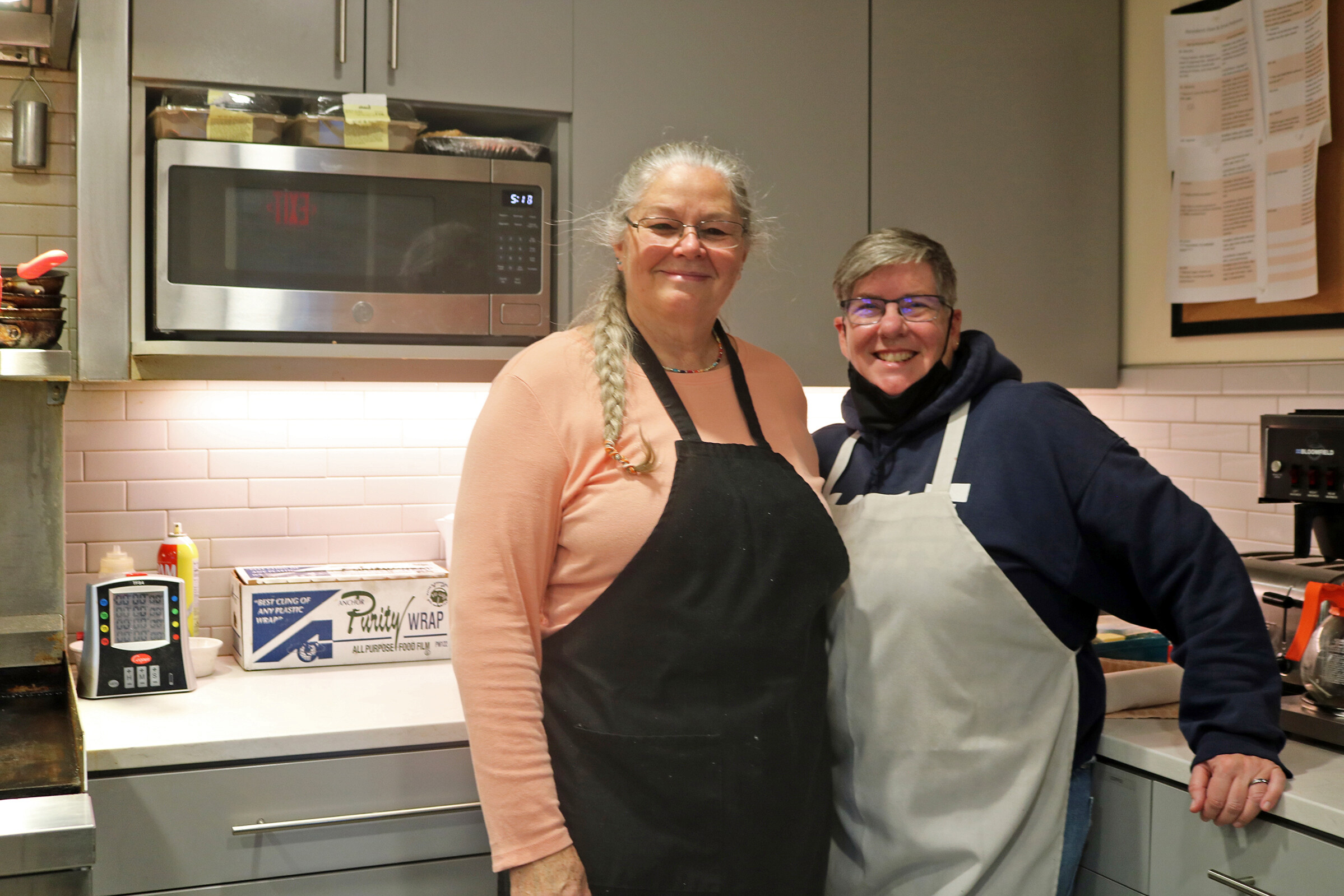 Volunteers Wanda Strickland (left) and Greta Getlein take a break during dinner preparations at Memory Care at Allen Brook in Williston.