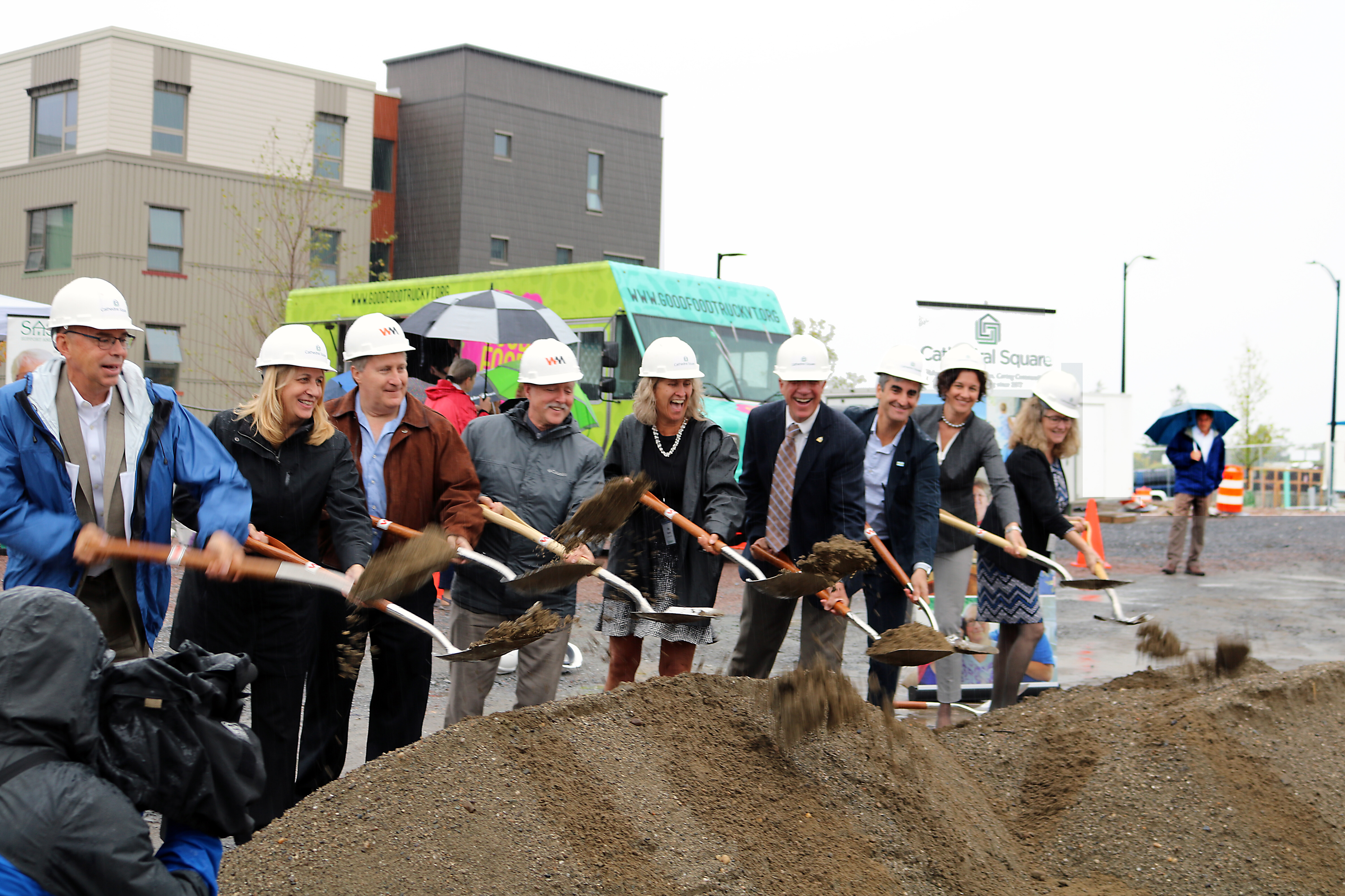 Several people lined up with shovels of dirt for groundbreaking celebration.