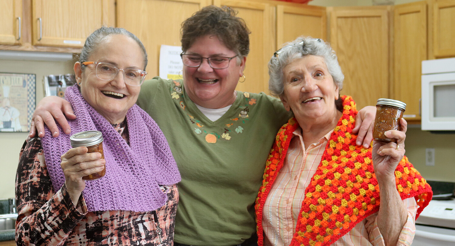 Cathedral Square residents Maria Charbonneau (left) and Theresa Hinman (right) are all smiles after receiving homemade chili and handmade shawls from Rose Cheeseman.