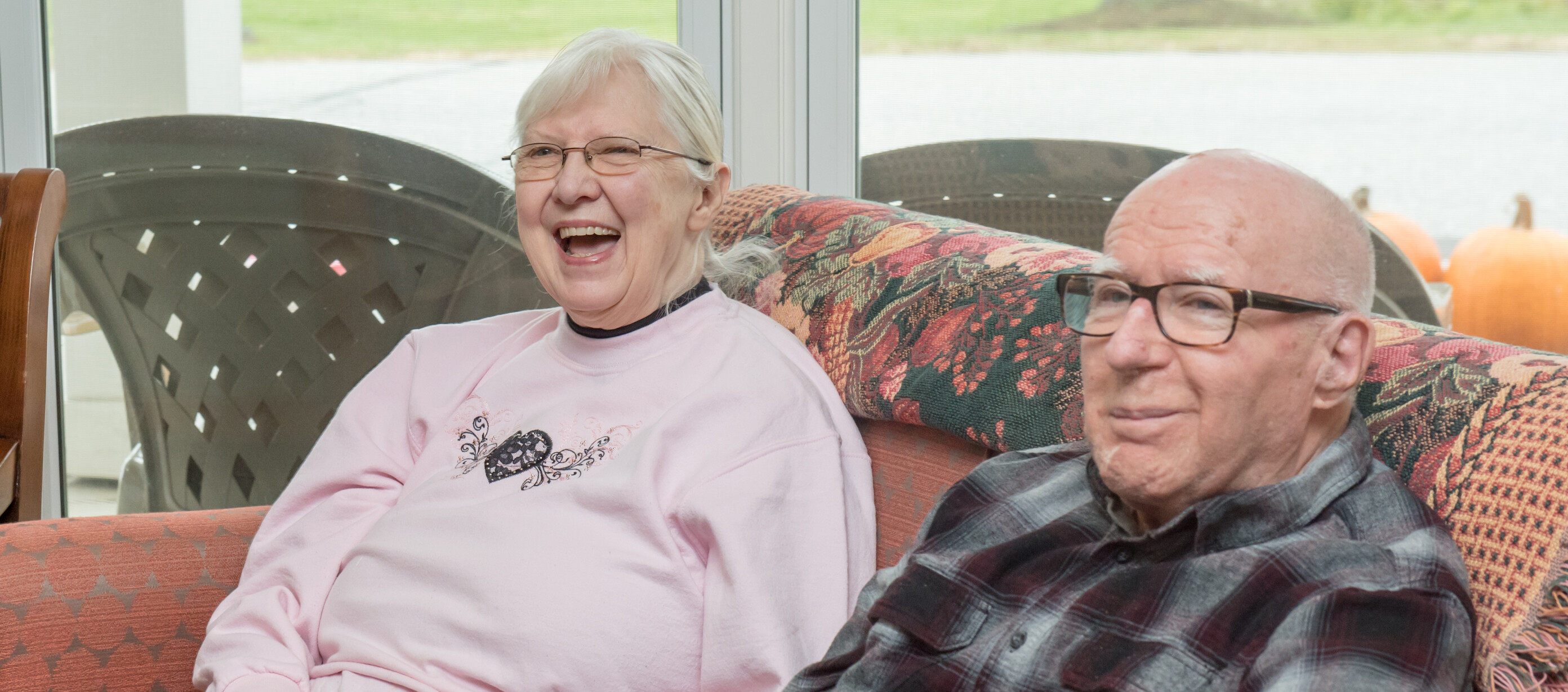 Two people sitting on a couch smiling and laughing.