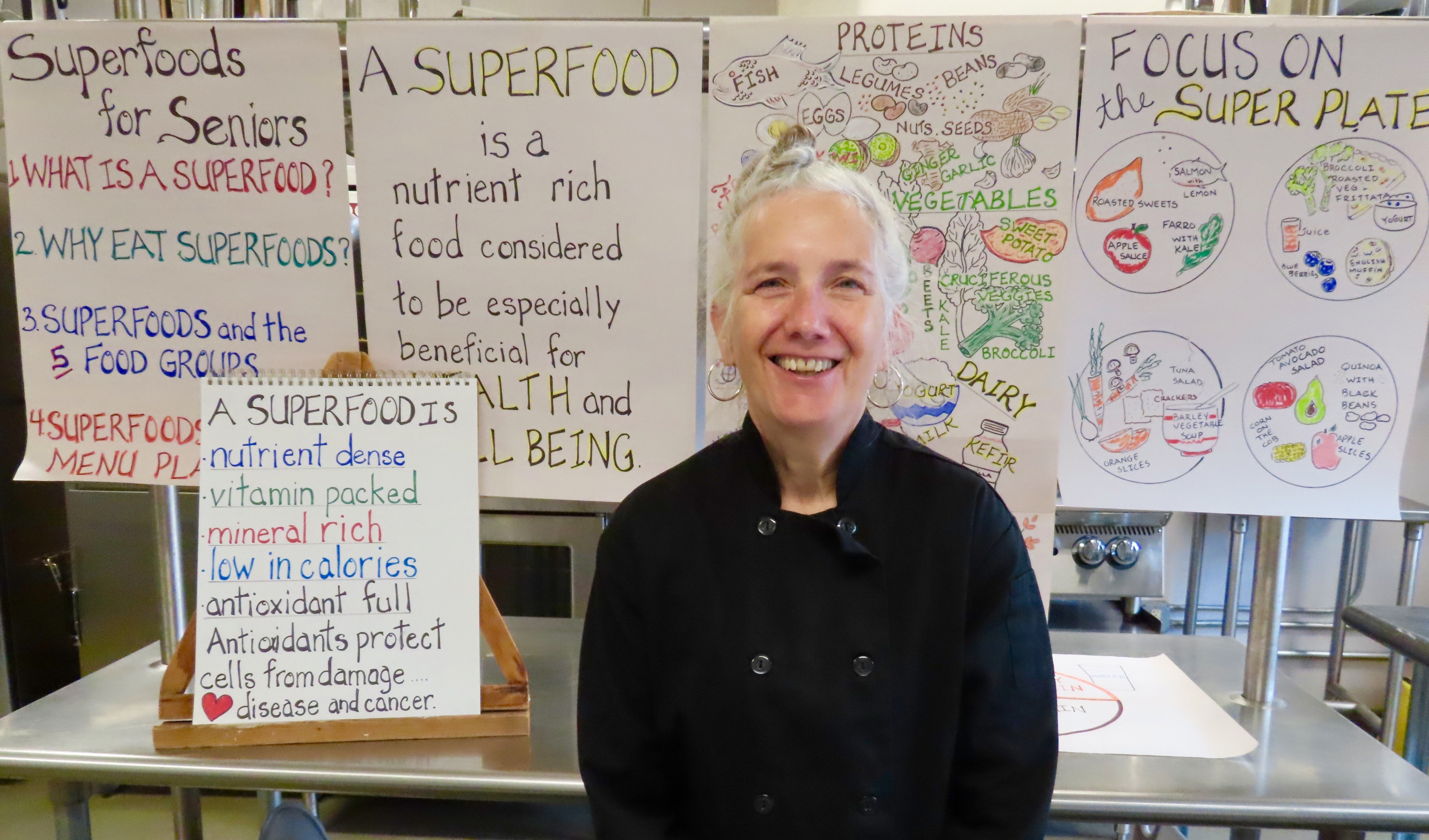 A photo of Chef Robin Burnett in a kitchen with several posters about nutrition behind her