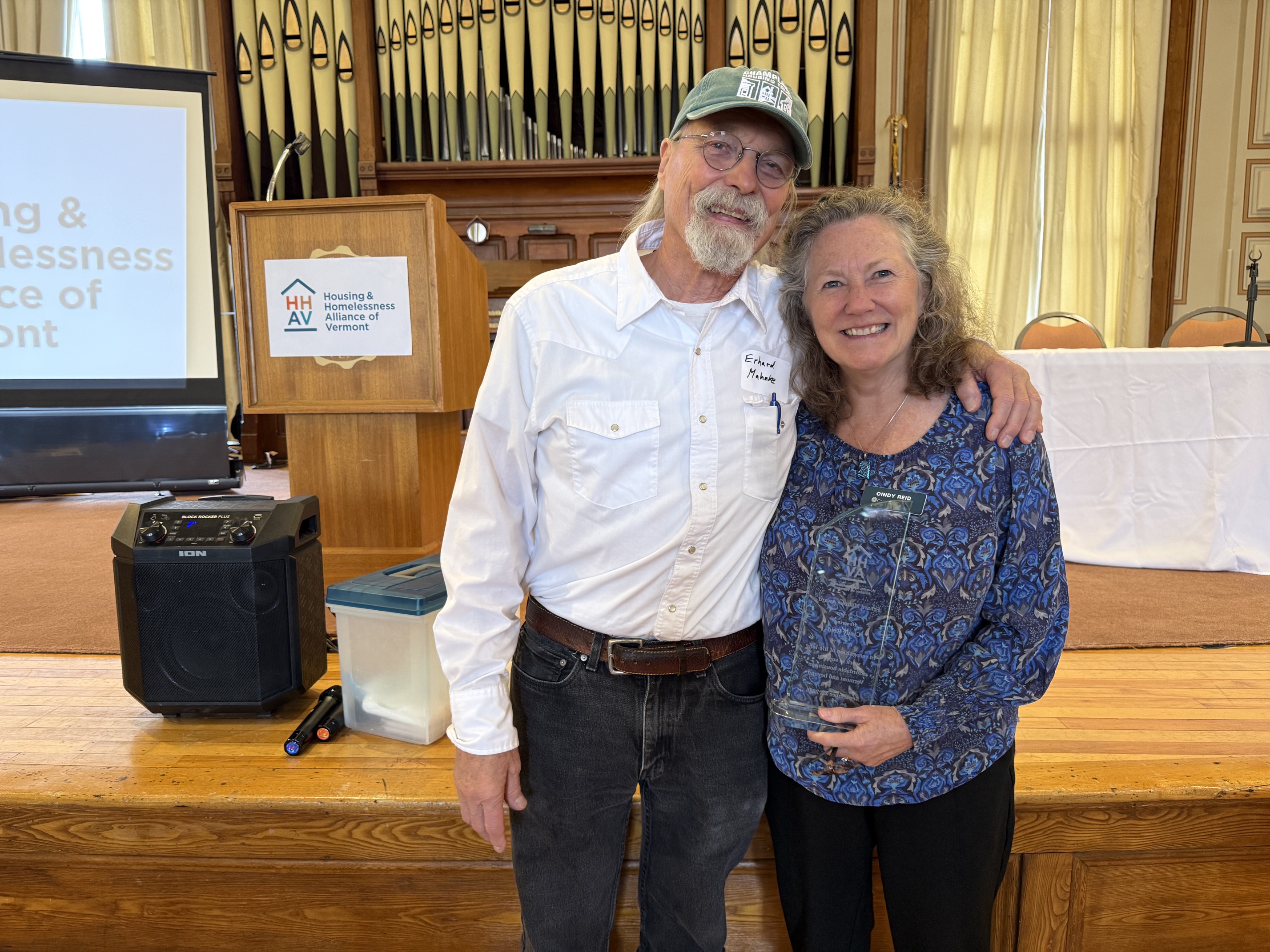 Award namesake Erhard Mahnke congratulates 2026 recipient Cindy Reid of Cathedral Square at the Housing & Homelessness Alliance of Vermont's annual meeting.