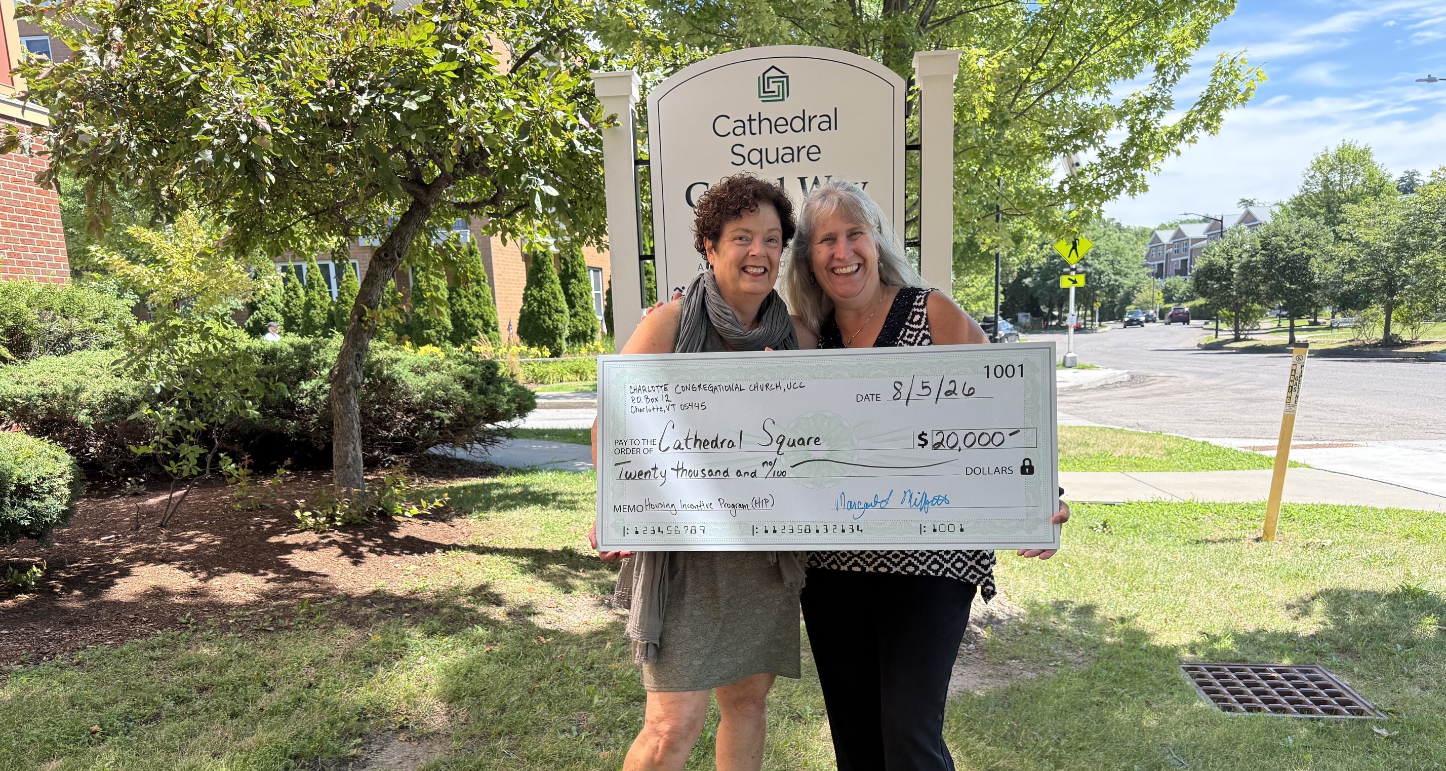 Photo of two people holding a big check
