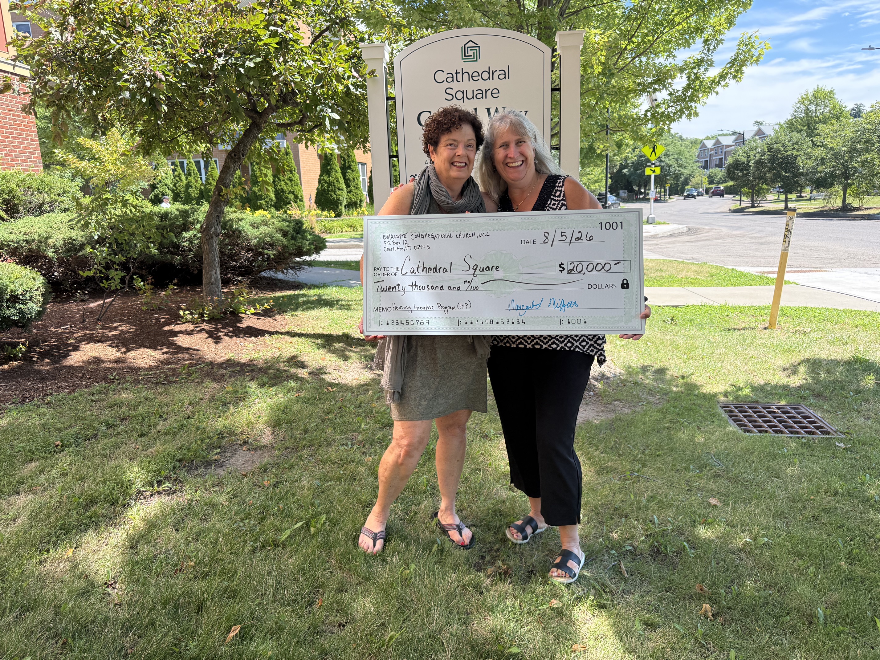 Photo of two people holding a big check